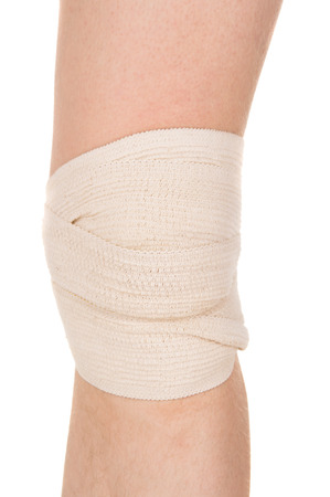 bandaging the knee with an elastic bandage isolated on white backgroundの写真素材