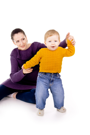 mother helps to do the first steps of the child isolated on white backgroundの写真素材