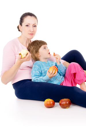 mother with a child eat apples isolated on white backgroundの写真素材