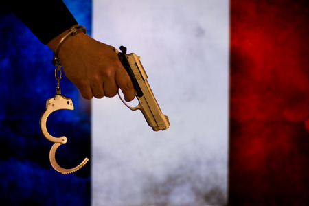 Crime and justice concept - Human hand holding gun and handcuff.の写真素材