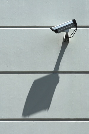 Security camera and big diagonal shadow on wall directedn along the wall watching private spaceの写真素材