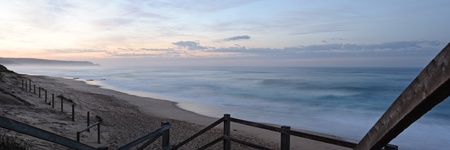 Panorama of large ocean surf waves at long exposure, clouds in sunrise light, surfing beach...