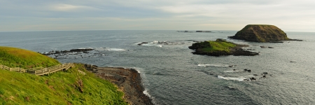 Panorama from Phillip Island with small Round Island facing South Ocean with green grass, rocks,...