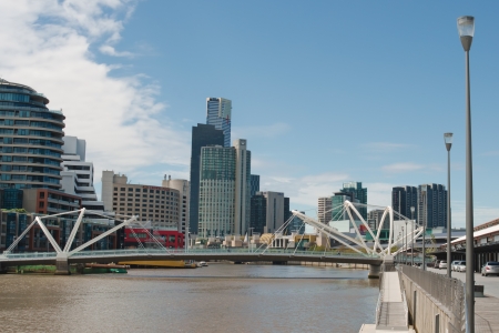 Footbridge Seafarers Bridge over Yarra River with skyscrapers in Southbank in background with brown water in Yarra and clouds in blue sky in Melbourne, Victoria, Australiaのeditorial素材