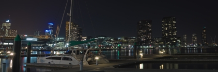 Night panorama at Victoria Harbor in Docklands with pier and catamaran moored in calm water and CBD lights in background in Victoria, Australiaのeditorial素材