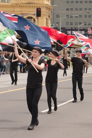 Row of flag carriers in black cloth with flags on street participating in Emirates Melbourne Cup Parade with crowds background on November 4, 2013 in Melbourne, Australiaのeditorial素材