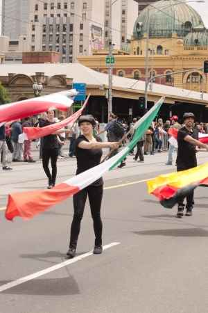 Flag carriers in black cloth walking and waving flags on Emirates Melbourne Cup Parade with crowds background on November 4, 2013 in Melbourne, Australiaのeditorial素材
