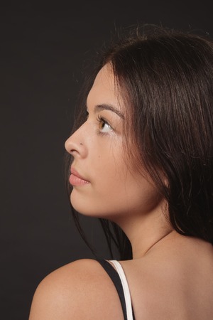 Attractive young brunet woman profile looking up over dark background