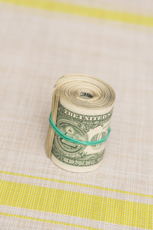A bundle of money twisted into a bundle and tied with a green rubber band