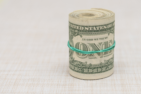 A bundle of money twisted into a bundle and tied with a green rubber band