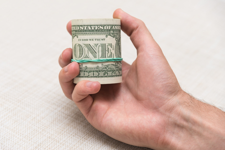 A man holds a bundle of money in his hand tied with an elastic bandの写真素材