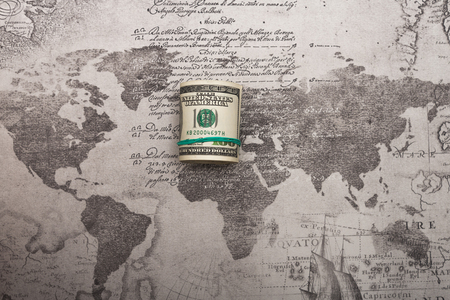A bundle of money tied with a green rubber band lying on the world mapの写真素材