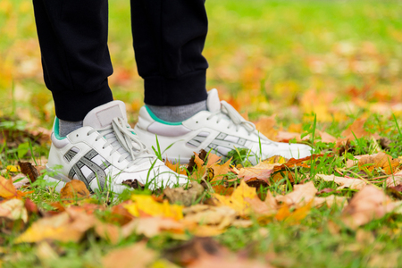 Men's white sneakers on their feet in the grassの写真素材