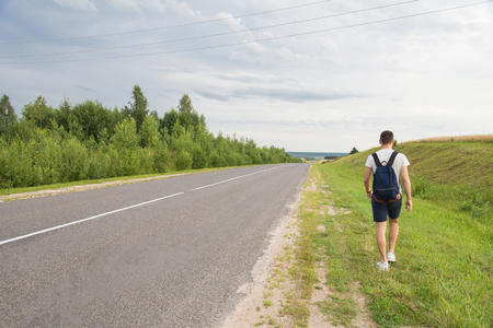 A man walking along the grass parallel to the roadの写真素材