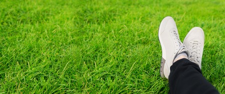 Female sneakers on legs in grassの写真素材