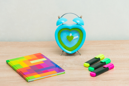 Multicolored blaknot located on a wooden background with a clock and markersの写真素材