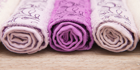 Multicolored towels on a wooden background lying next to each otherの写真素材