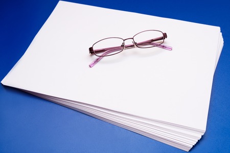 Mock up, a pack of white paper with glasses on a blue backgroundの写真素材