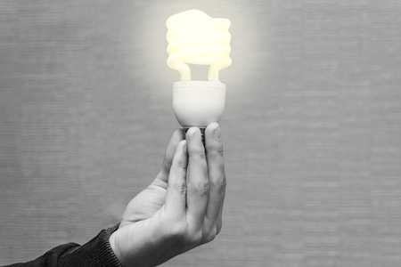 Energy-saving burning light in the hands of a man on a light backgroundの写真素材