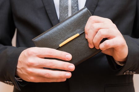 A man in a suit is holding a book
