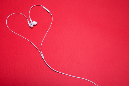 White headphones lined in the form of a heart on a red backgroundの写真素材