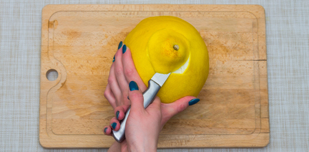 Girl cleans a pomelo on a wooden board