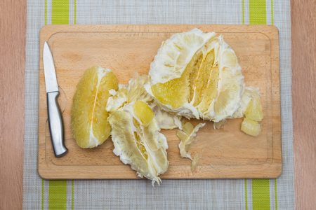 Cleansed pomelo and knife lying on a wooden boardの写真素材