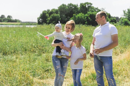 Family walks in the field. With soap bubbles. A family with two children. The family is in the same...