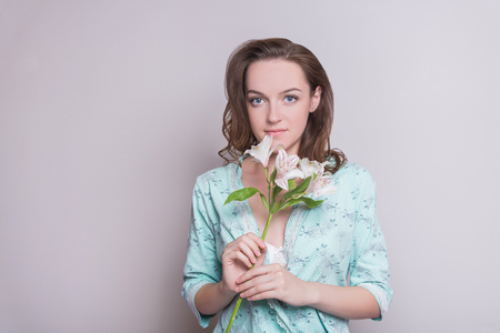 Woman with a flower. Woman on white background. A girl is holding flowers in her hands on a white background.の写真素材