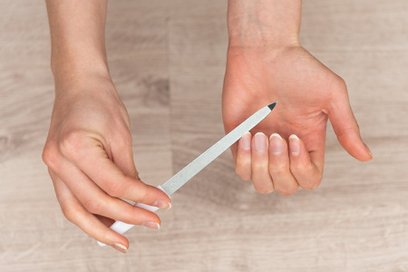 Manicure on female hands. A woman makes a manicure. Nail file in female hands.の写真素材