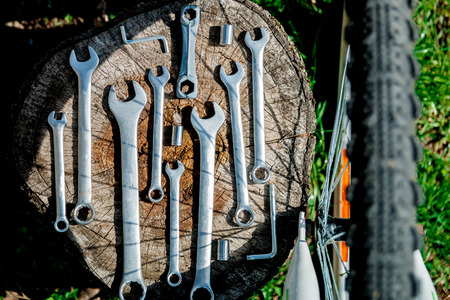 bicycle repair tools on wooden background, top view. Bike repairing, green outside background.の写真素材