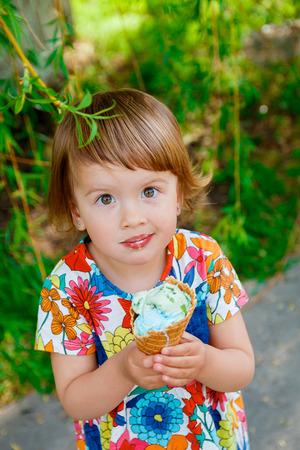 Cute and happy little girl eating ice cream outsideの写真素材