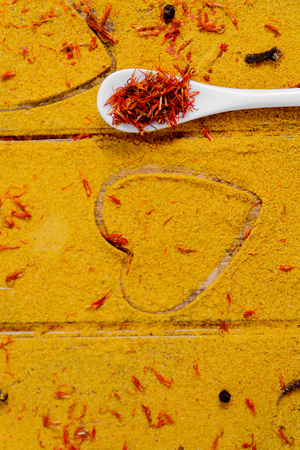 Heart of spices and seasonings. White spoon with saffron on curry background.  Various spices selection. Closeup. Copy Space. Loveの写真素材