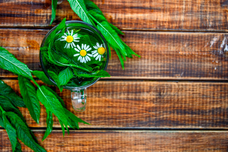 A cup of mint tea with chamomile on a wooden background. herbal tea with chamomile and fresh mint leaves on table. Copy space. Frame. Top view.の写真素材