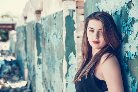 Portrait of Beautiful, long haired, dark-haired girl in a black T-shirt on an abandoned house. Attractive womanposing in old ruined factory house. Copy space. Tone photoの写真素材