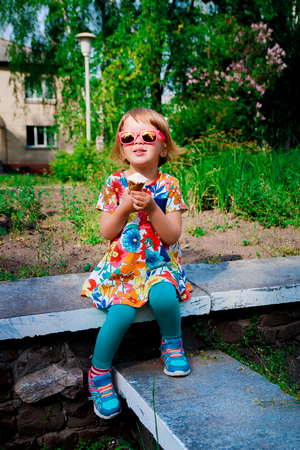 Cute and happy young girl eating ice cream outsideの写真素材