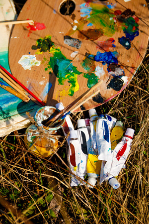 Artist's Palette with paints and brushes on grass backgroundの写真素材