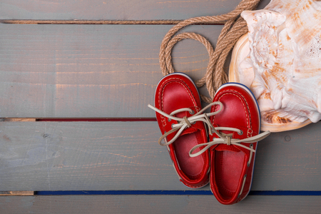 Red boat shoes near big shell and rope on wooden background. Top view/. Copy space. Frame.の写真素材