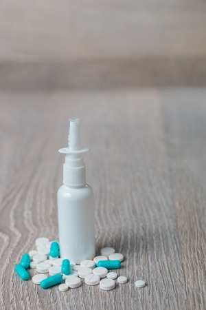 Blue and white medication, pills and spray on grey wooden background. Copy space. Close up.の写真素材