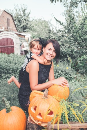 Halloween. Daughter hugging mother near jack-o-lantern in the garden. Decoration for party. Happy family.の写真素材