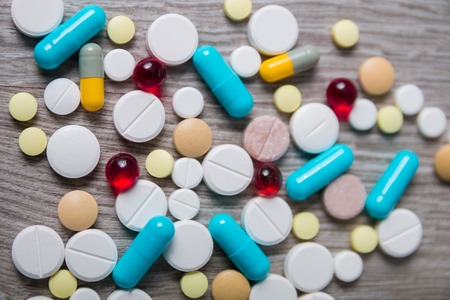 A lot of colorful medication and pills from above on grey wooden background. Copy space. Top view,...