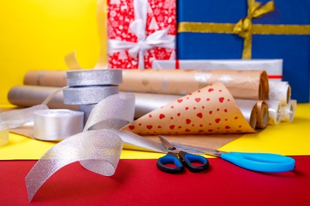 Gift wrapping, boxes, paper, ribbon and scissors on color background. Materials and accessories for wrapping presents. Close up.の写真素材