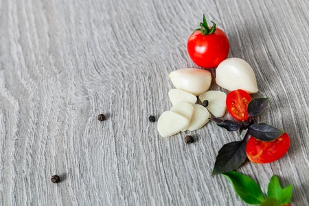 Cherry tomatoes, garlic and fresh basil on grey wooden background. Frame.の写真素材