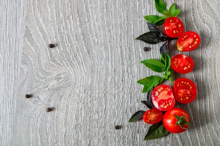 Cherry tomatoes and fresh basil on grey wooden background. Frame.の写真素材