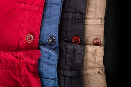 Fragment of four cotton twill pants red, blue, black, beige with open buttons.の写真素材