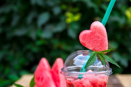 Watermelon cocktail with slice outdoor. Heart carved from watermelon on the tube. Close up,の写真素材