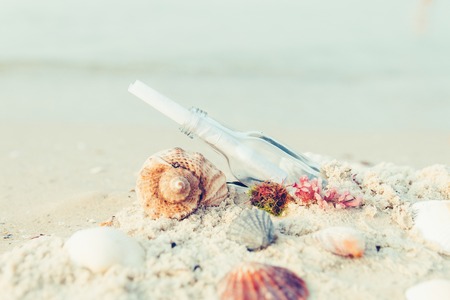 Bottle with a message or letter on the beach near seashell. SOS.の写真素材