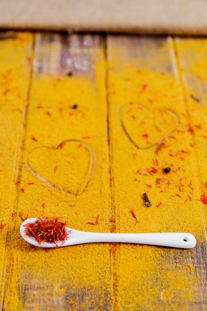 Heart of spices and seasonings. White spoon with saffron on curry background.  Various spices selection. Closeup. Copy Space. Loveの写真素材