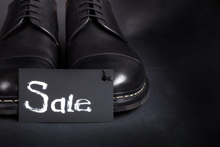 Sale sign. Black oxford shoes on black background. Back view. Copy space.の写真素材