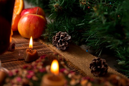 Christmas decoration on table. Candles, pine cone, fruit, spruce on wooden background. New year